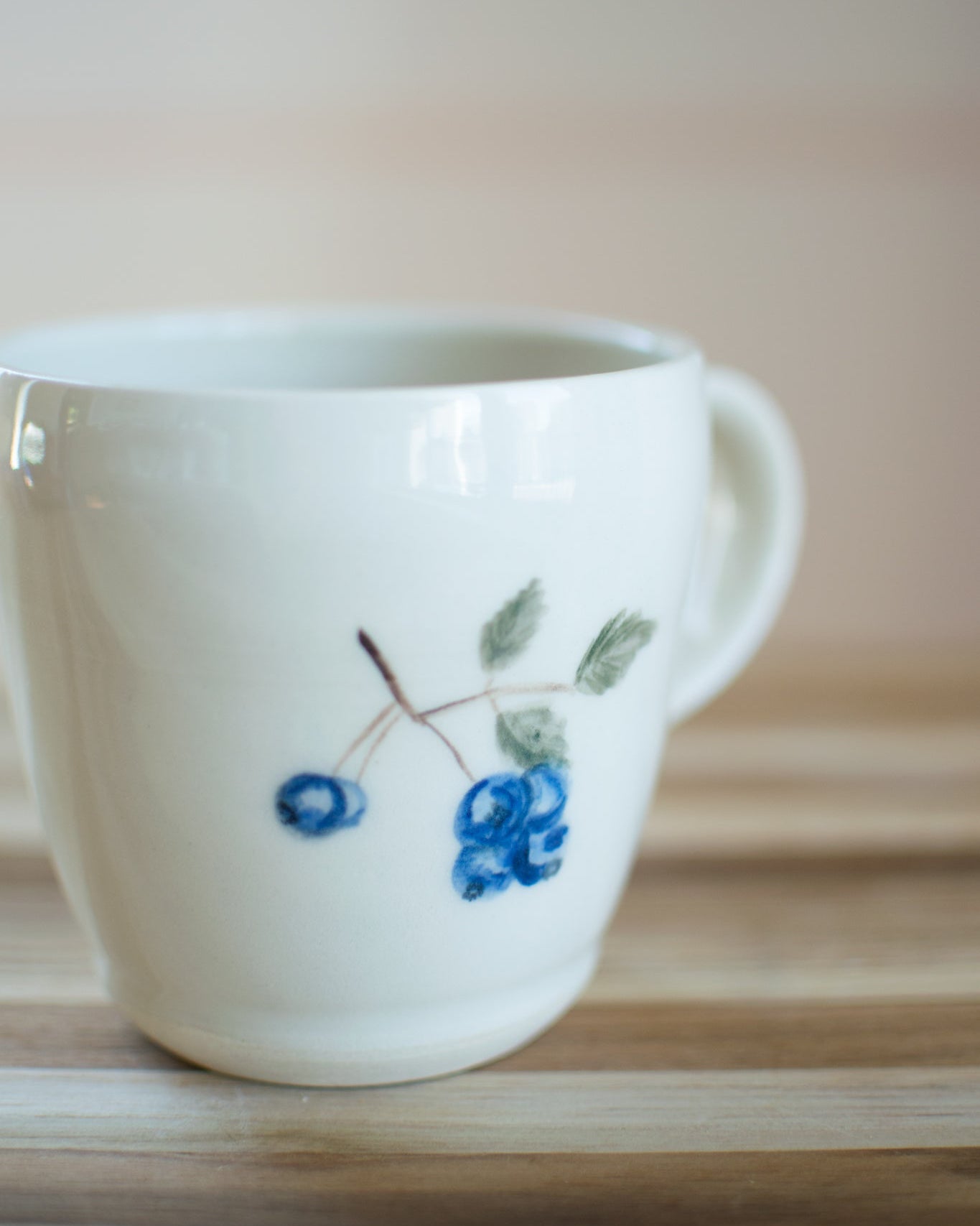 White mug with blue floral design on a wooden surface