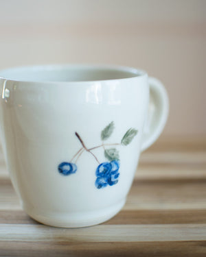 White mug with blue floral design on a wooden surface