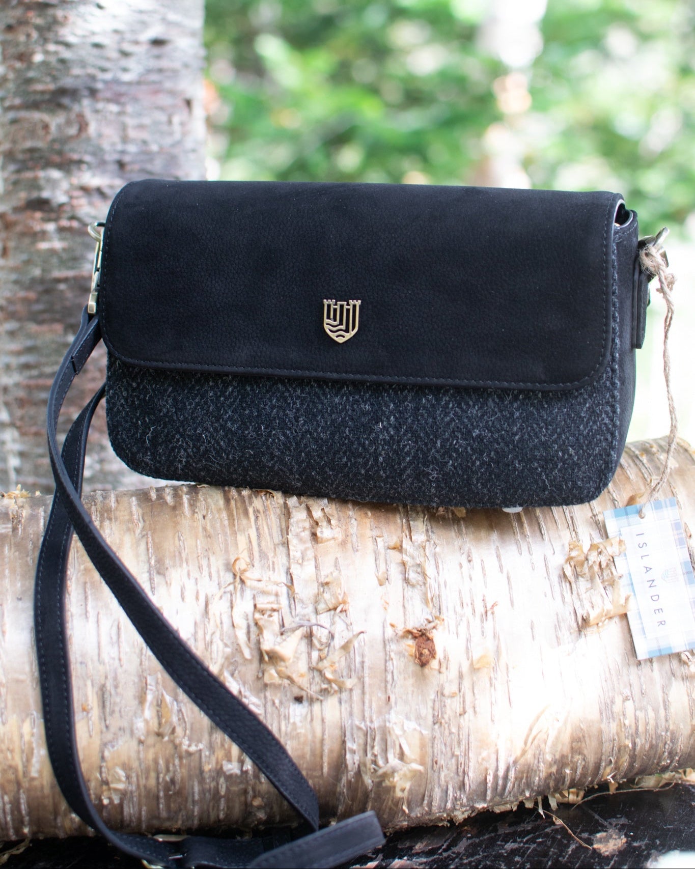 Black handbag with a gold emblem on a tree branch