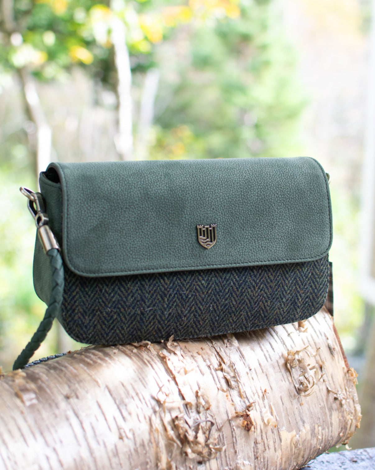 Green crossbody bag on a tree branch with a blurred natural background