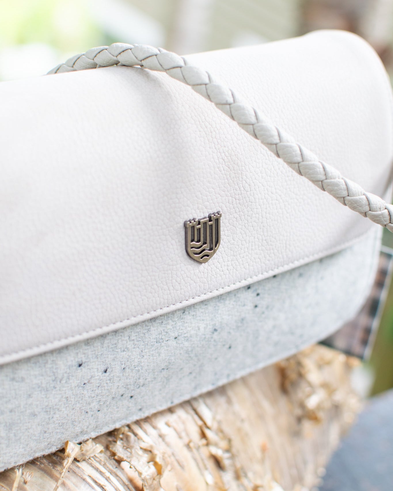 White handbag with a brand logo on a tree branch in a forest setting