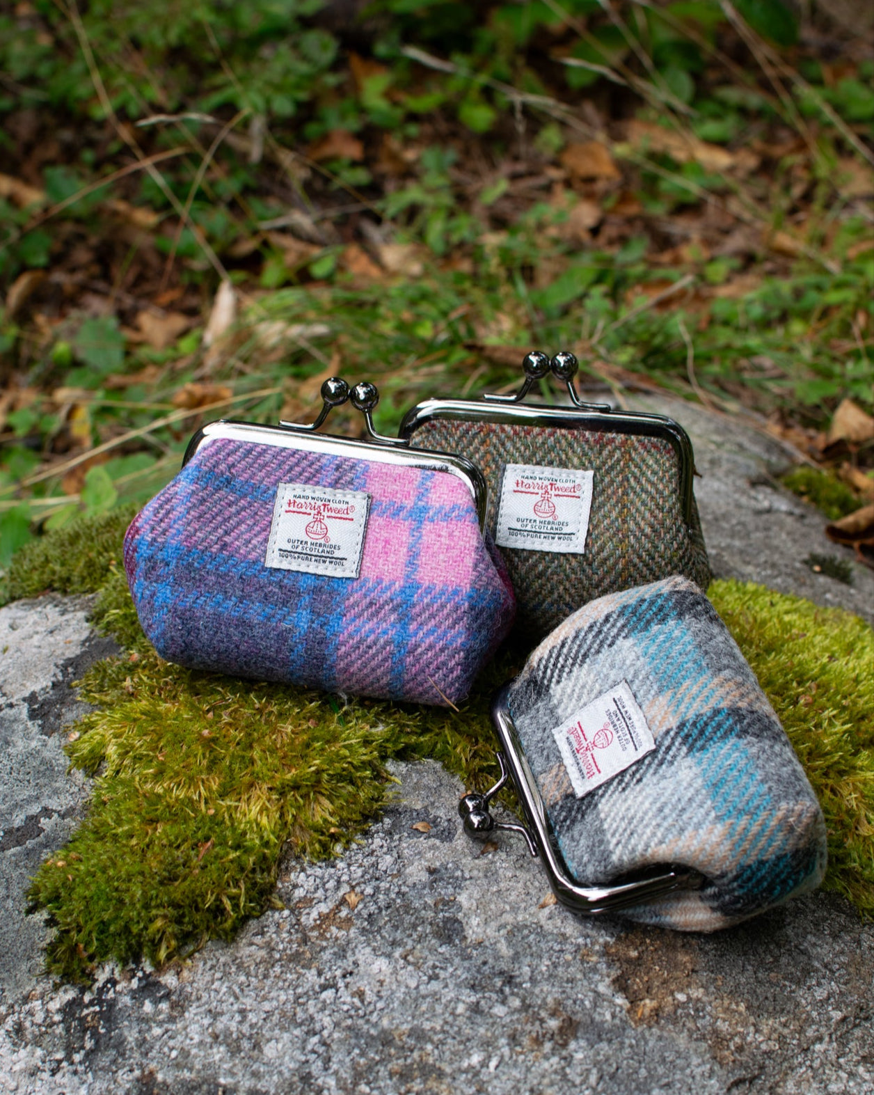 Three plaid coin purses on a rock with a natural background