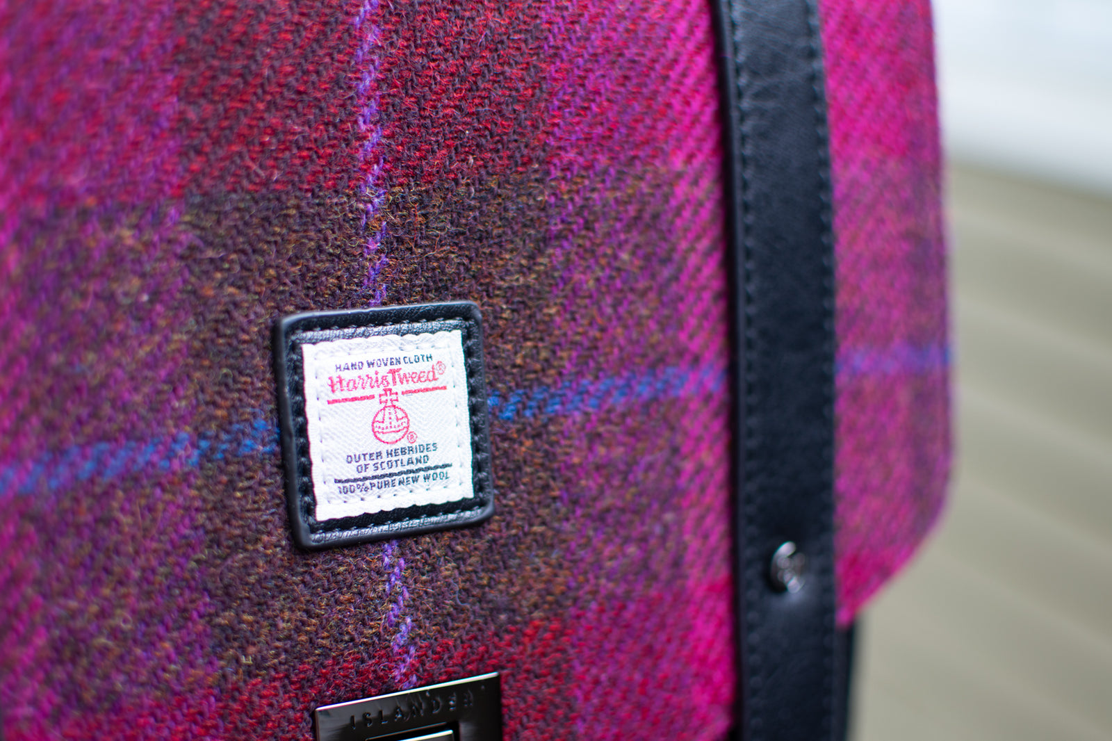 Backpack with pink plaid pattern and black accents on a wooden surface with a blurred natural background
