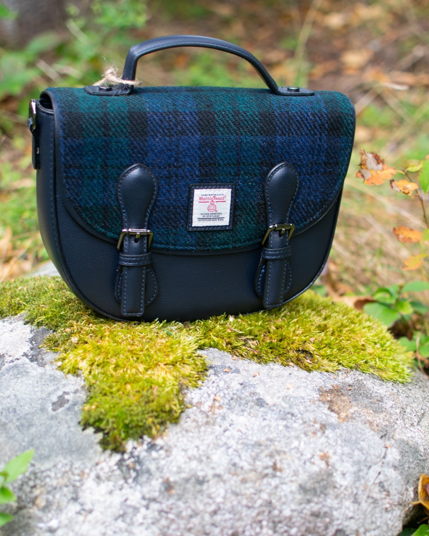 Four bags in green and black plaid pattern on a log with a forest background