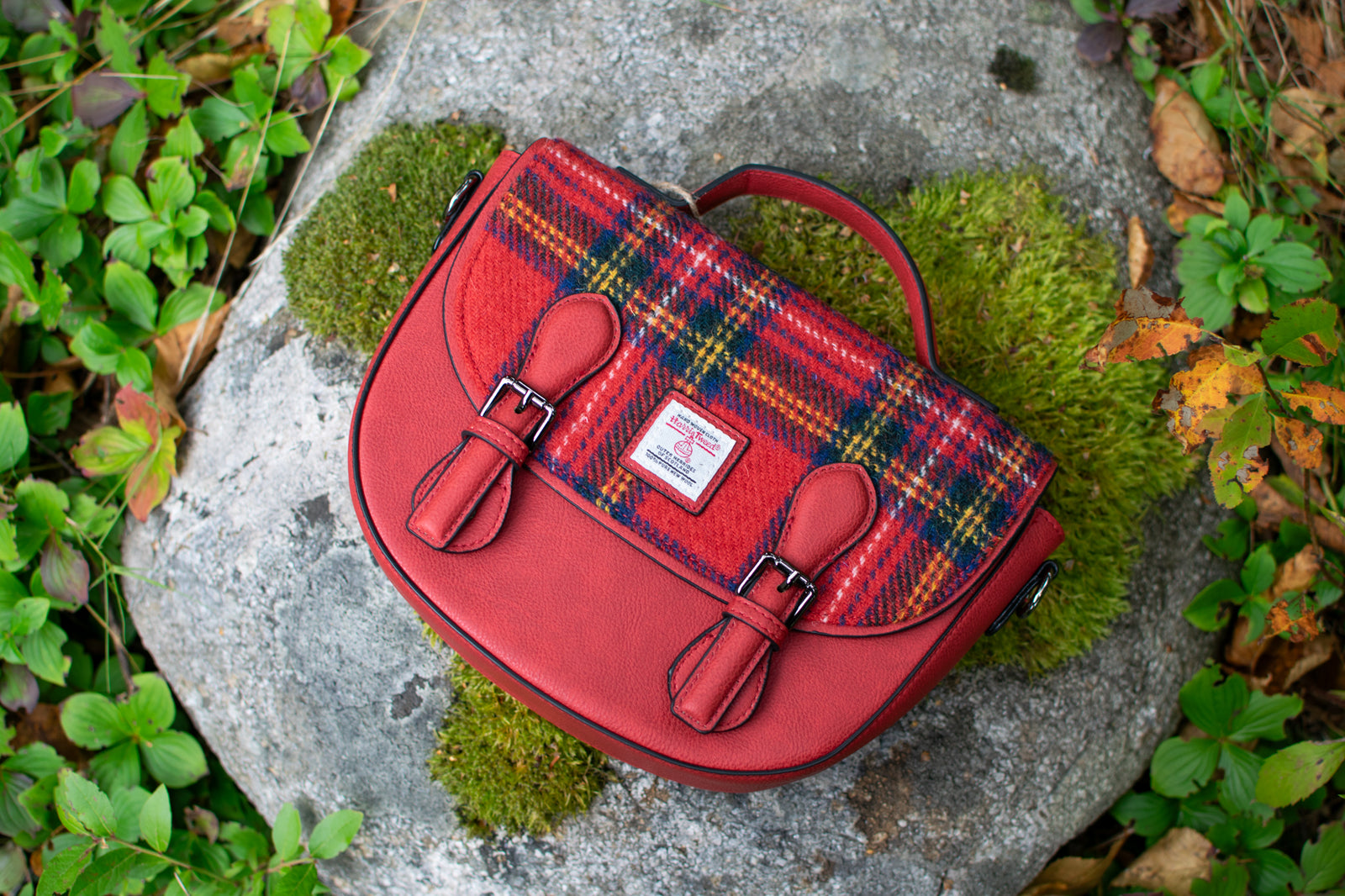 Red plaid bag on a rock with greenery in the background