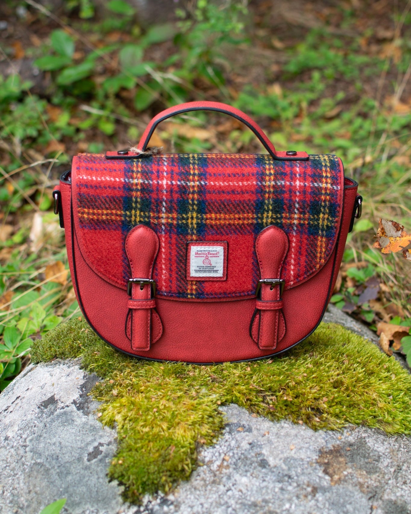 Red plaid bag on a rock with greenery in the background