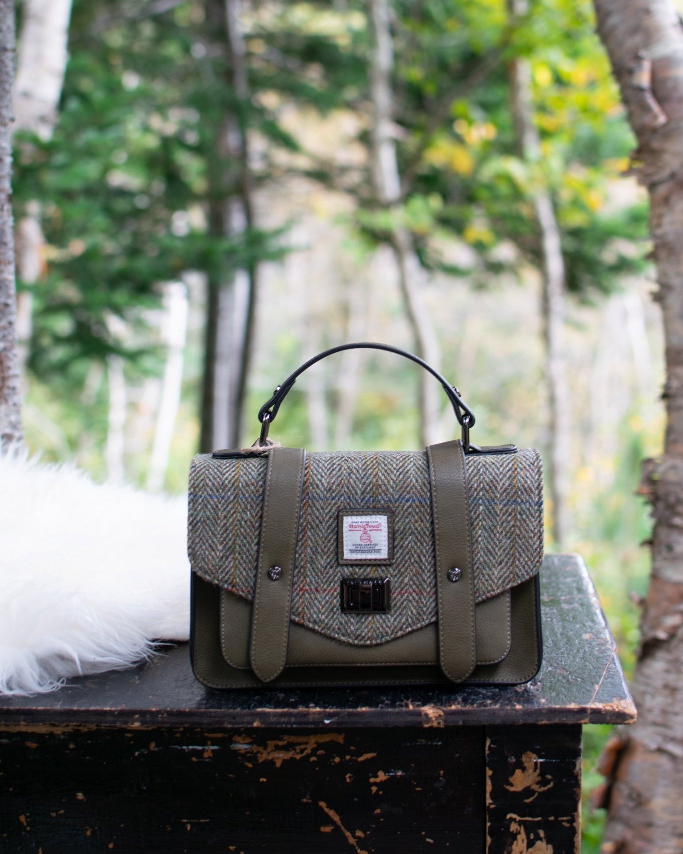 Green textured handbag on a wooden surface with a forest background