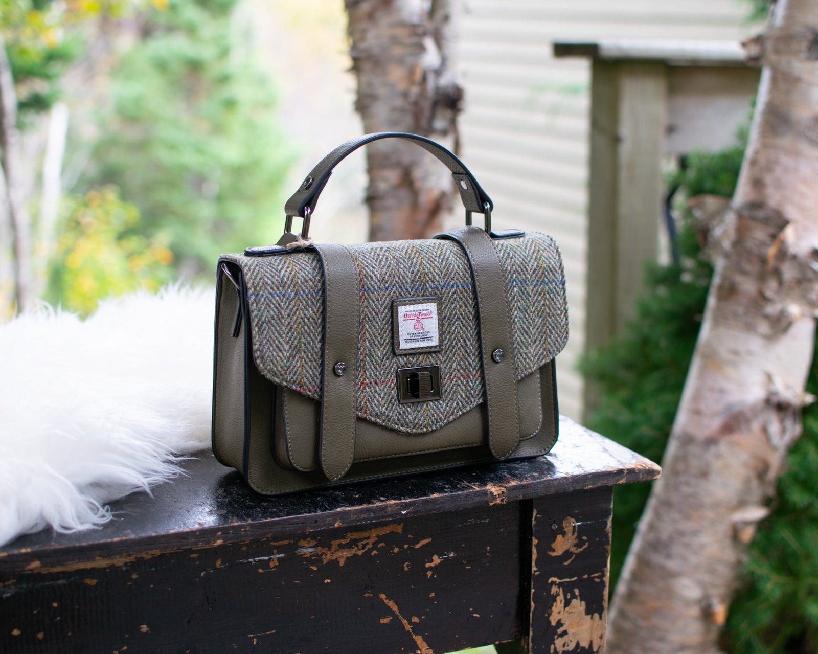 Green textured handbag on a wooden surface with a forest background
