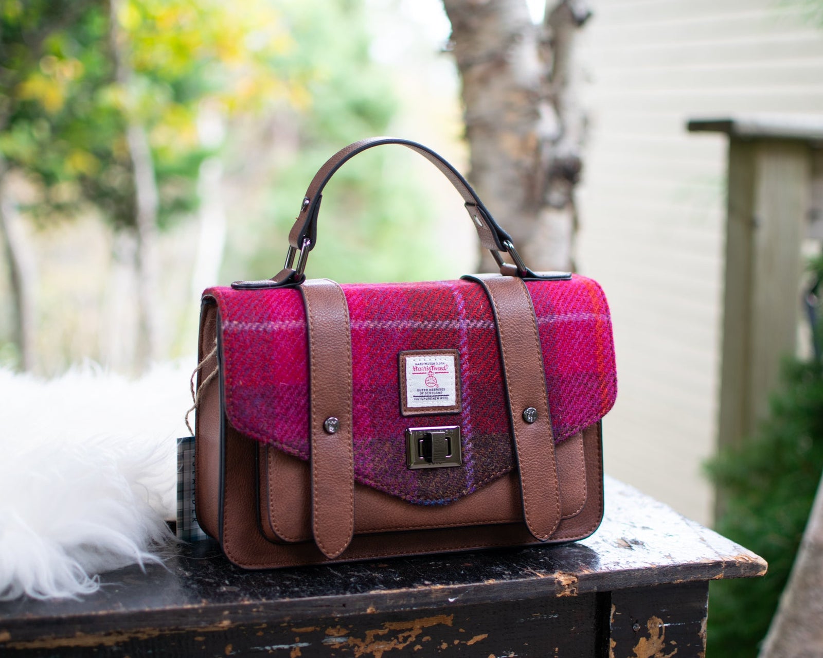 Pink and brown checkered bag on a wooden table with a forest background