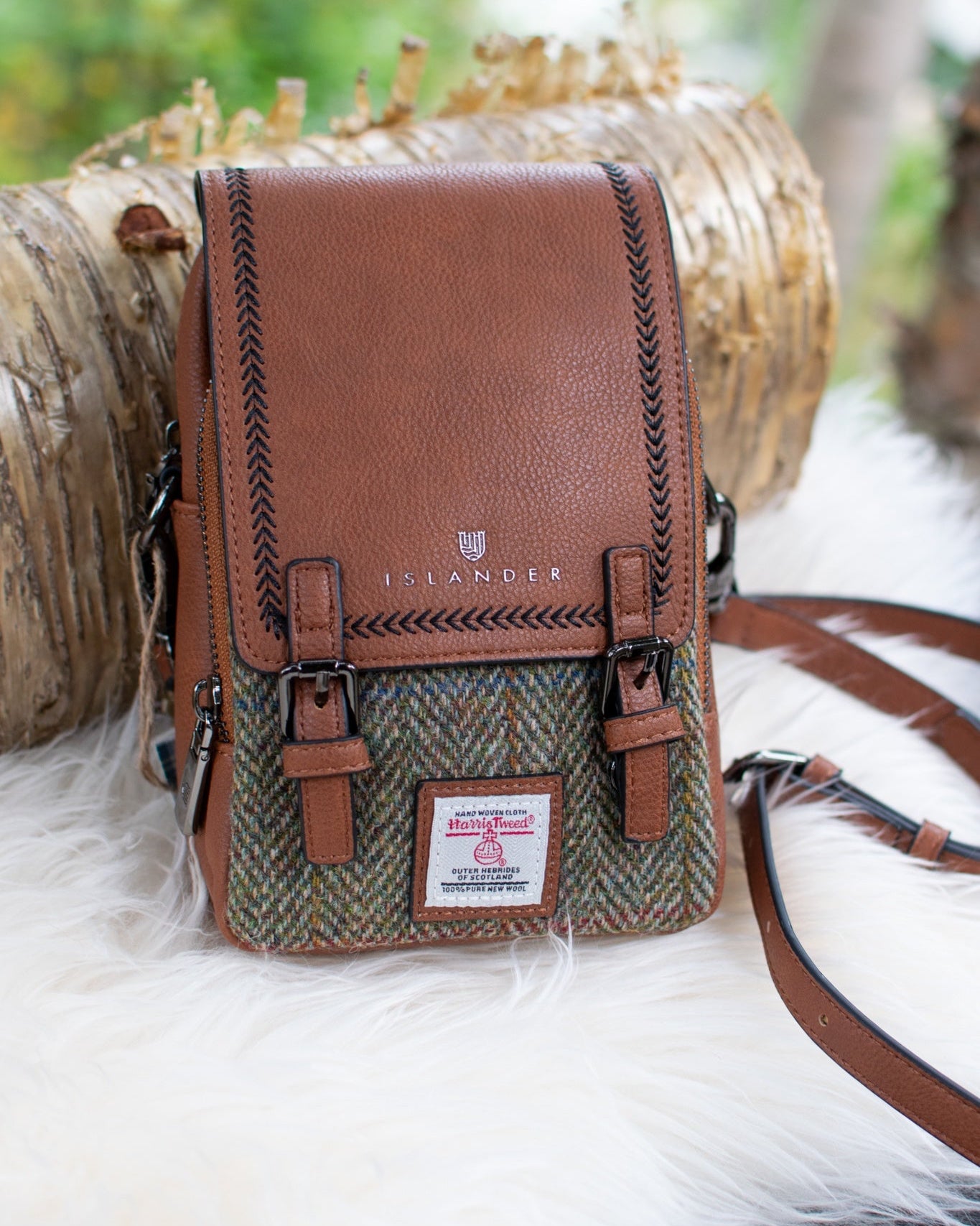 Brown leather and tweed bag with a visible brand label on a white fur surface.