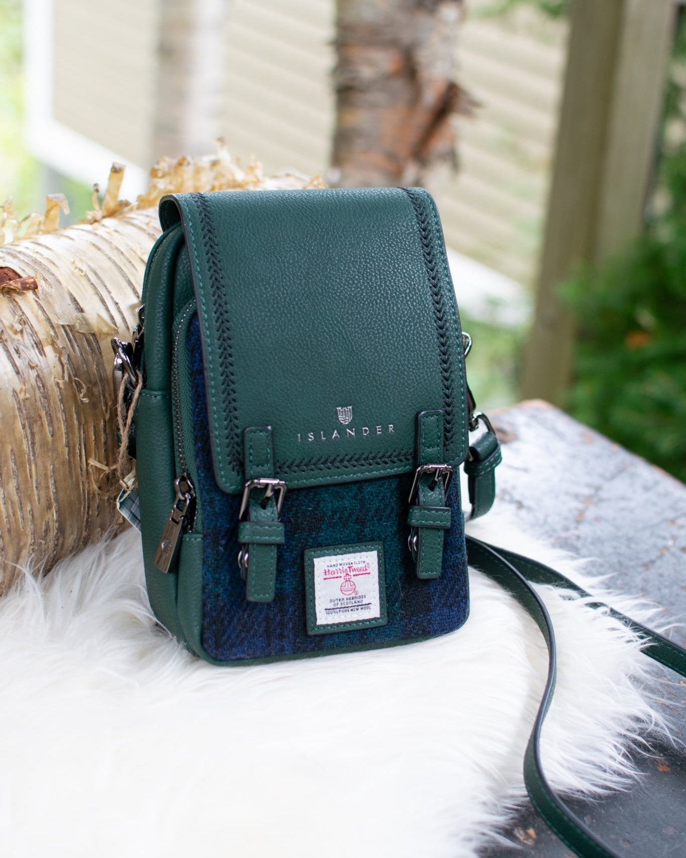 Green crossbody purse with straps on a white surface with blurred natural background