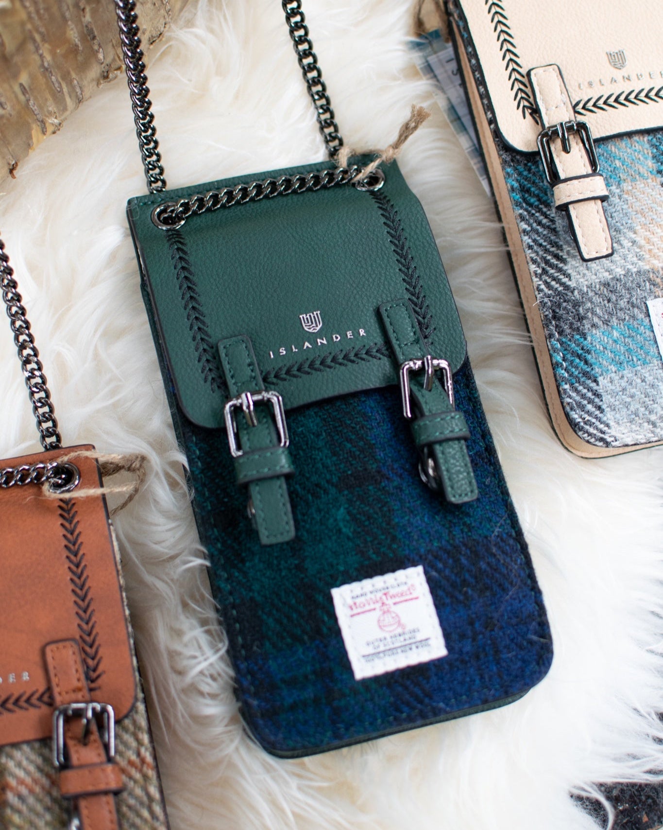 Green and blue plaid crossbody bag with chain strap on a textured surface