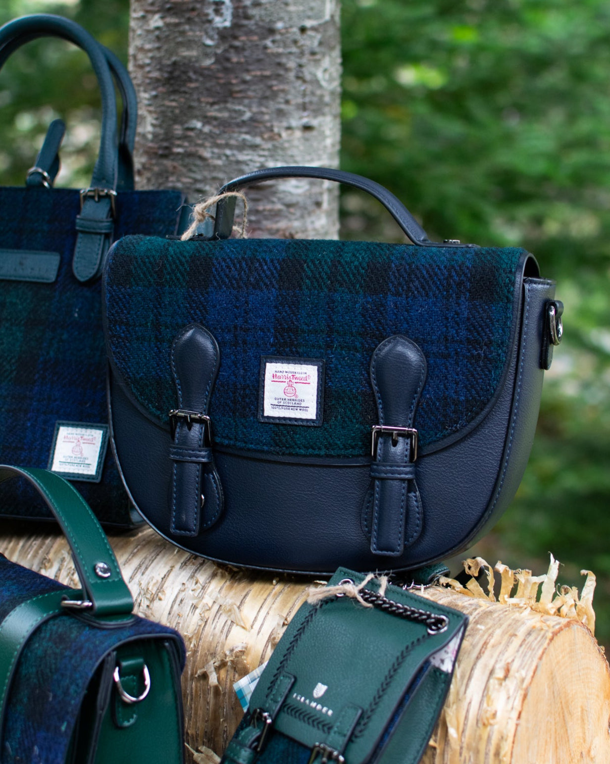 Four bags in green and black plaid pattern on a log with a forest background